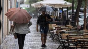 Dos personas con paraguas por Madrid.