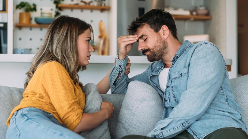 Pareja discutiendo en el sofá de su casa.