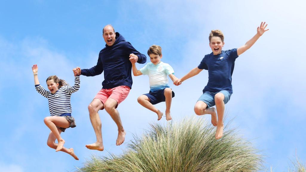 El príncipe Guillermo junto a sus tres hijos, divertidos, saltando en la playa.