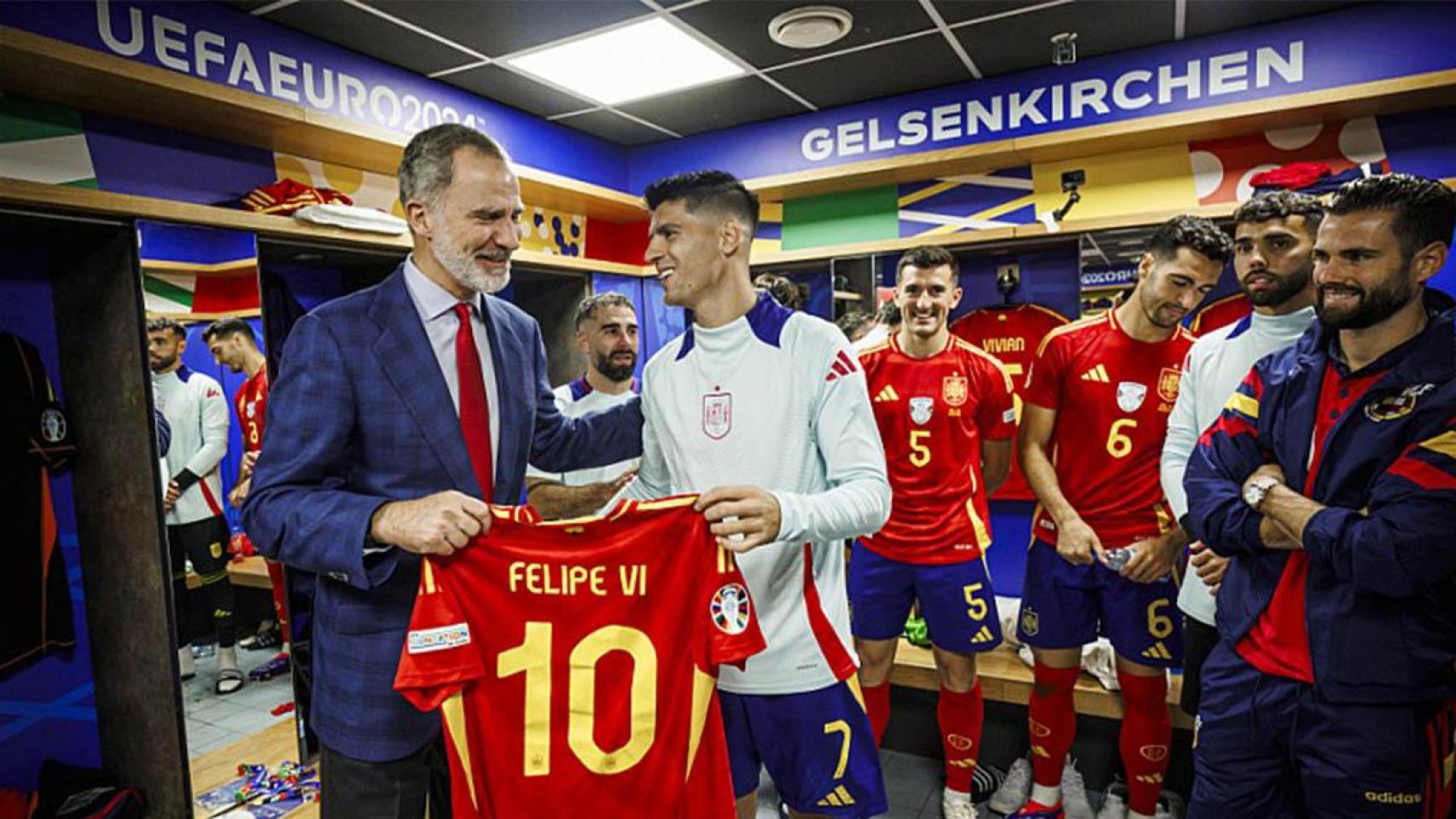 El Rey Felipe VI recibe una camiseta con su nombre tras felicitar a los jugadores de España por el triunfo ante Italia.