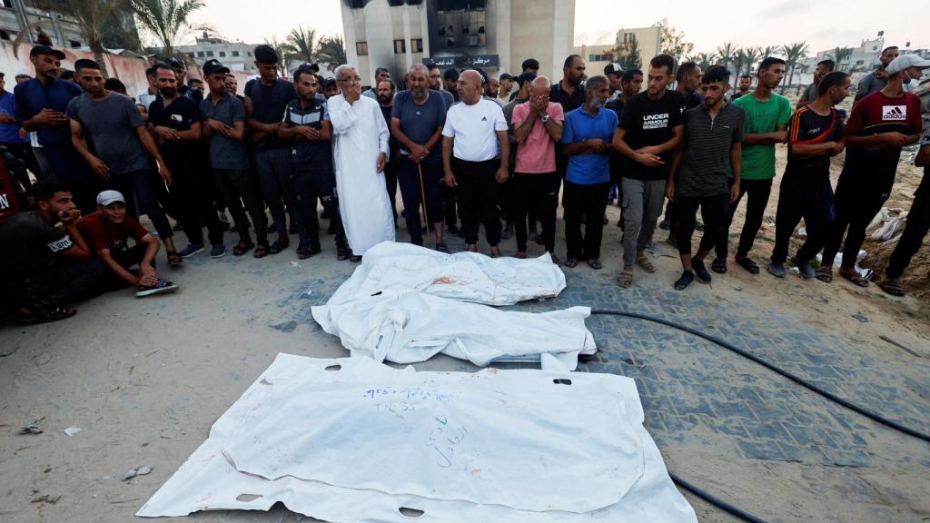 Un grupo de palestinos junto a cadáveres de víctimas del ataque israelí a  un campamento de Al-Mawasi este viernes.