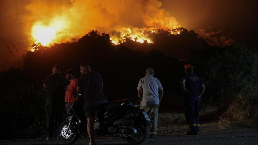 Los lugareños observan un incendio forestal en el pueblo de Latas (Grecia).