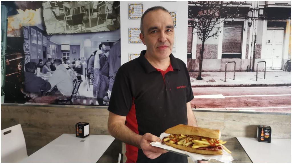 El propietario del Bar Rogelio posa con un Caníbal 8. Al fondo, varias fotografías del local que ocupaban cuando abrió por primera vez en A Coruña