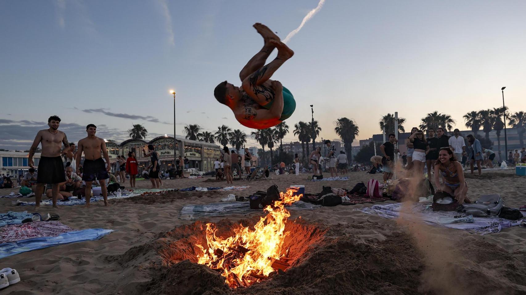 Un joven salta una hoguera, en la playa de la Malvarrosa, en Valencia.