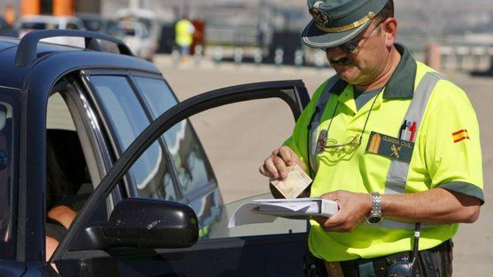Un agente de la Guardia Civil poniendo una multa a un conductor.