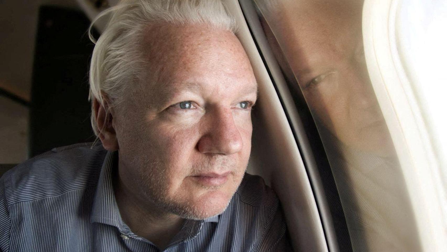 Julian Assange mira a través de la ventanilla de su avión al llegar al aeropuerto de Bangkok.