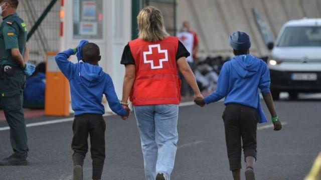 Una trabajadora de Cruz Roja escolta a dos menores migrantes, en una foto de archivo.
