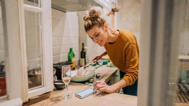 Mujer cocinando y mirando el móvil.