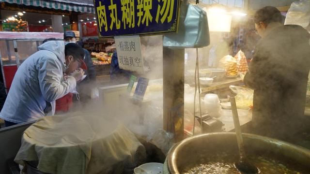 Varias personas disfrutan de puestos de comida en las calles de Xian.