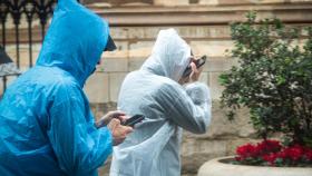 Dos personas se protegen de la lluvia en Sevilla con un chubasquero.