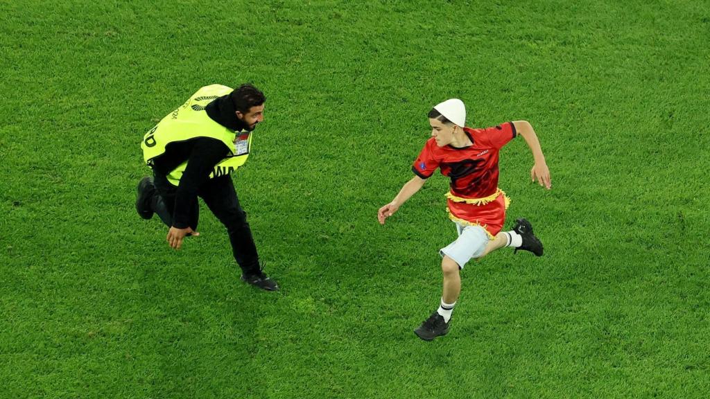 Un vigilante persigue a un espontáneo durante el partido entre Albania y España.