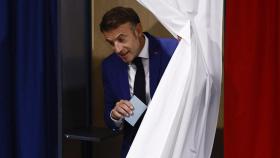 El presidente francés Emmanuel Macron sale de una cabina de votación, al visitar un colegio electoral para votar en la primera vuelta de las elecciones parlamentarias anticipadas en Francia, en Le Touquet-Paris-Plage, el 30 de junio de 2024.