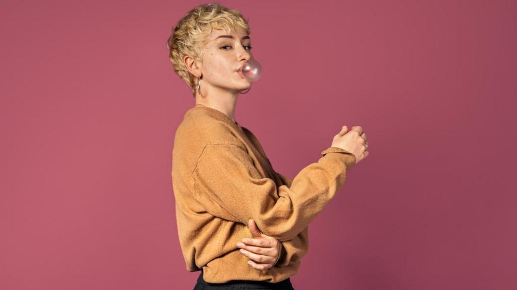 Mujer con el pelo corto haciendo un globo con un chicle.