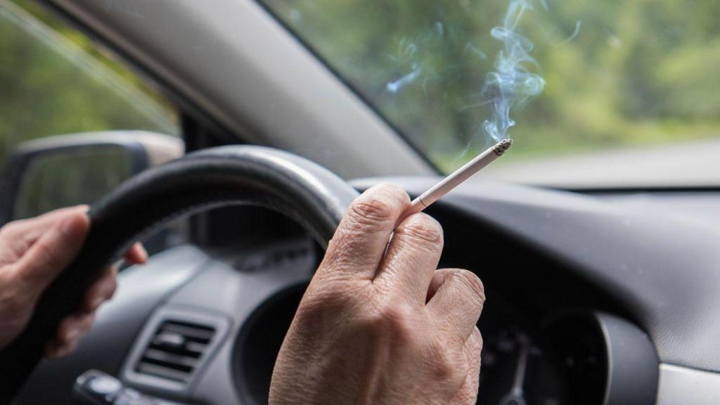 Una persona fumando dentro de un coche.