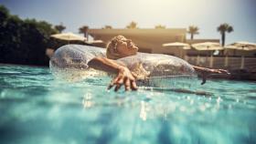 Mujer disfrutando en la piscina con un flotador.