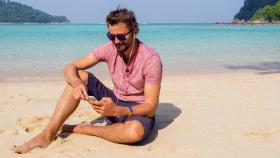 Un hombre usando su teléfono móvil en una playa.