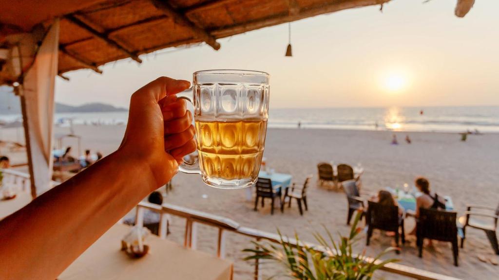 Una persona con una cerveza en la playa.