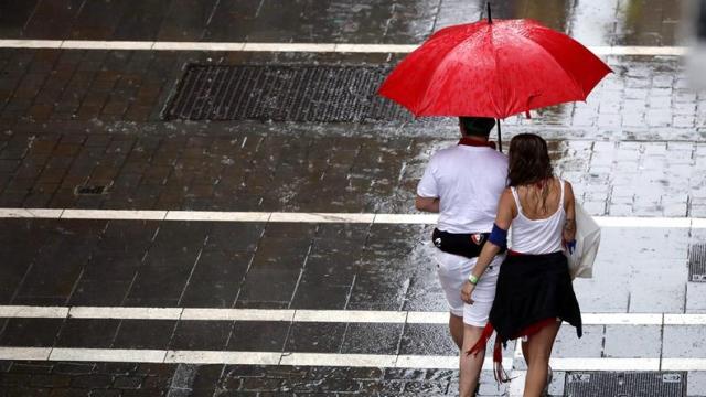 Dos personas caminando bajo la lluvia durante San Fermín.