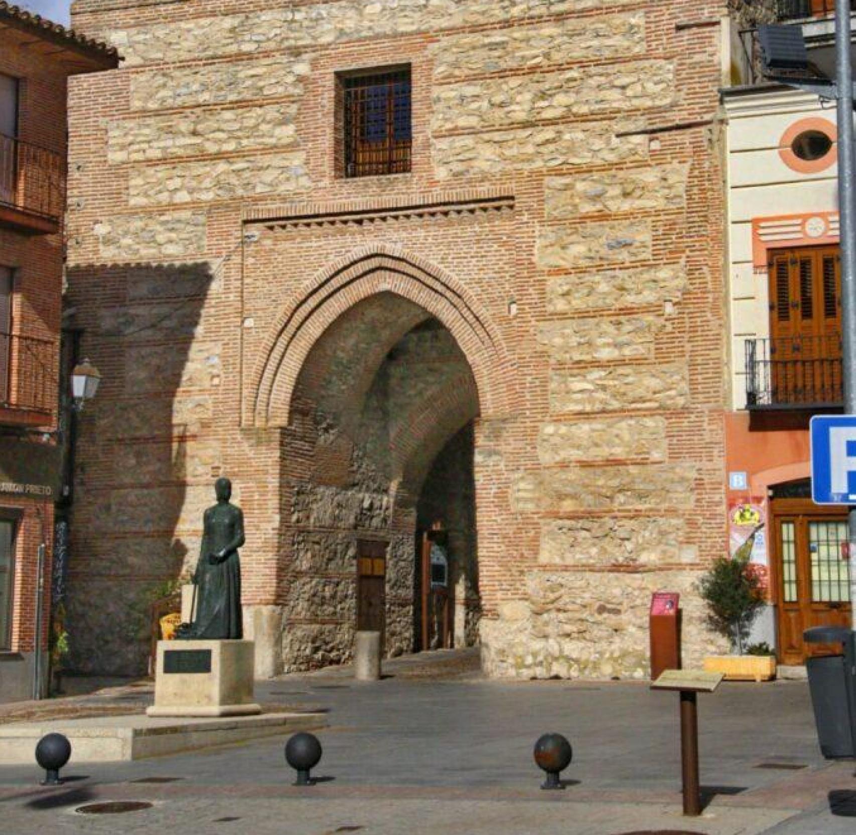 Arco del Alcocer y, delante, una estatua de Isabel de Católica