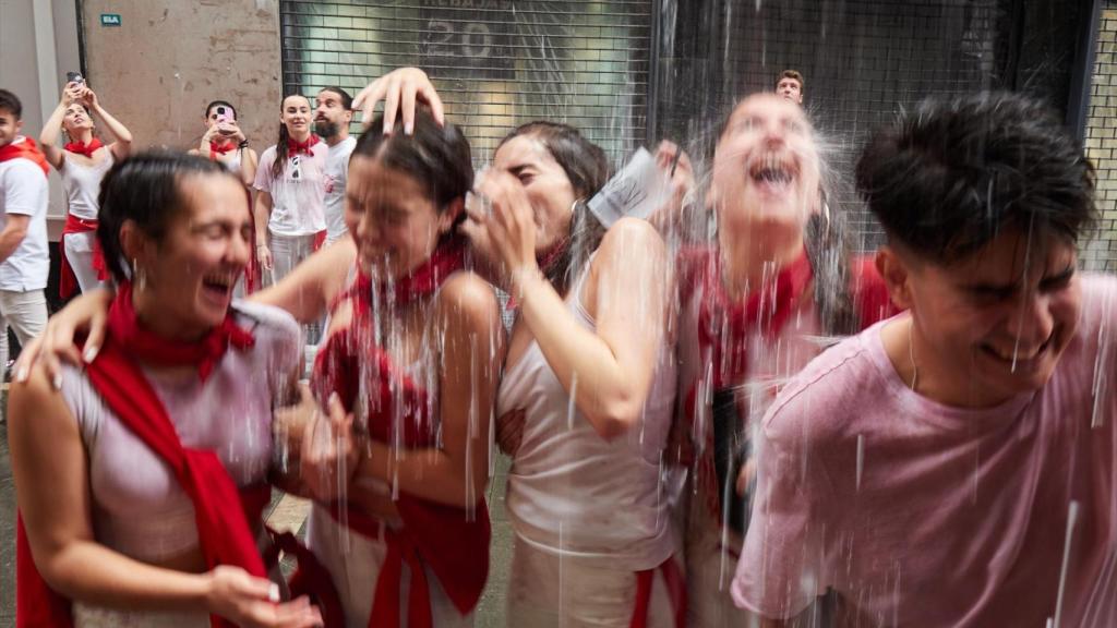 Varias personas celebran el comienzo de las fiestas de San Fermín durante el txupinazo.