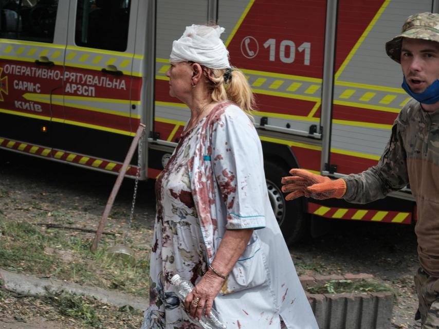 Una enfermera del hospital infantil de Kiev, con una herida en la cabeza y la ropa cubierta de sangre, intenta ayudar tras el ataque ruso.