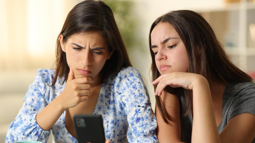 Amigas mirando el móvil con cara de preocupación.