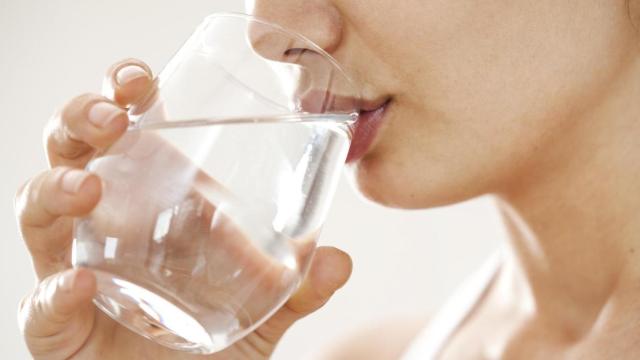 Mujer bebiendo un vaso de agua.