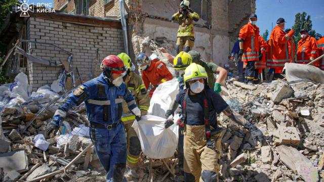 Rescatistas llevan el cuerpo de una persona encontrada bajo los escombros en el lugar donde un edificio de apartamentos fue alcanzado por un ataque con misiles rusos, en medio del ataque de Rusia a Ucrania, en Kiev.