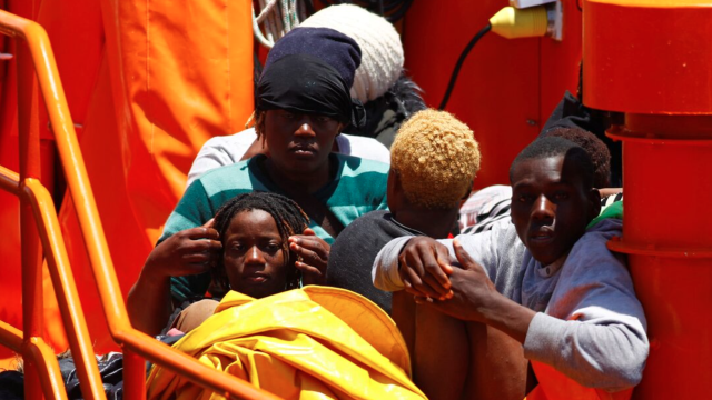 Inmigrantes esperan desembarcar de un bote de la guardia costera española en el puerto de Arguineguin.