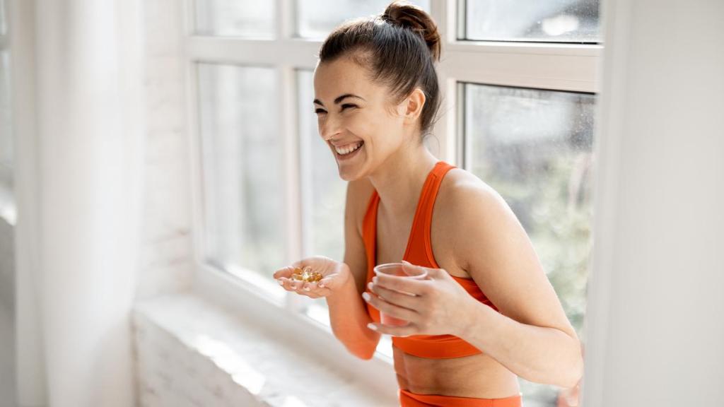 Mujer deportista tomando un suplemento alimenticio.