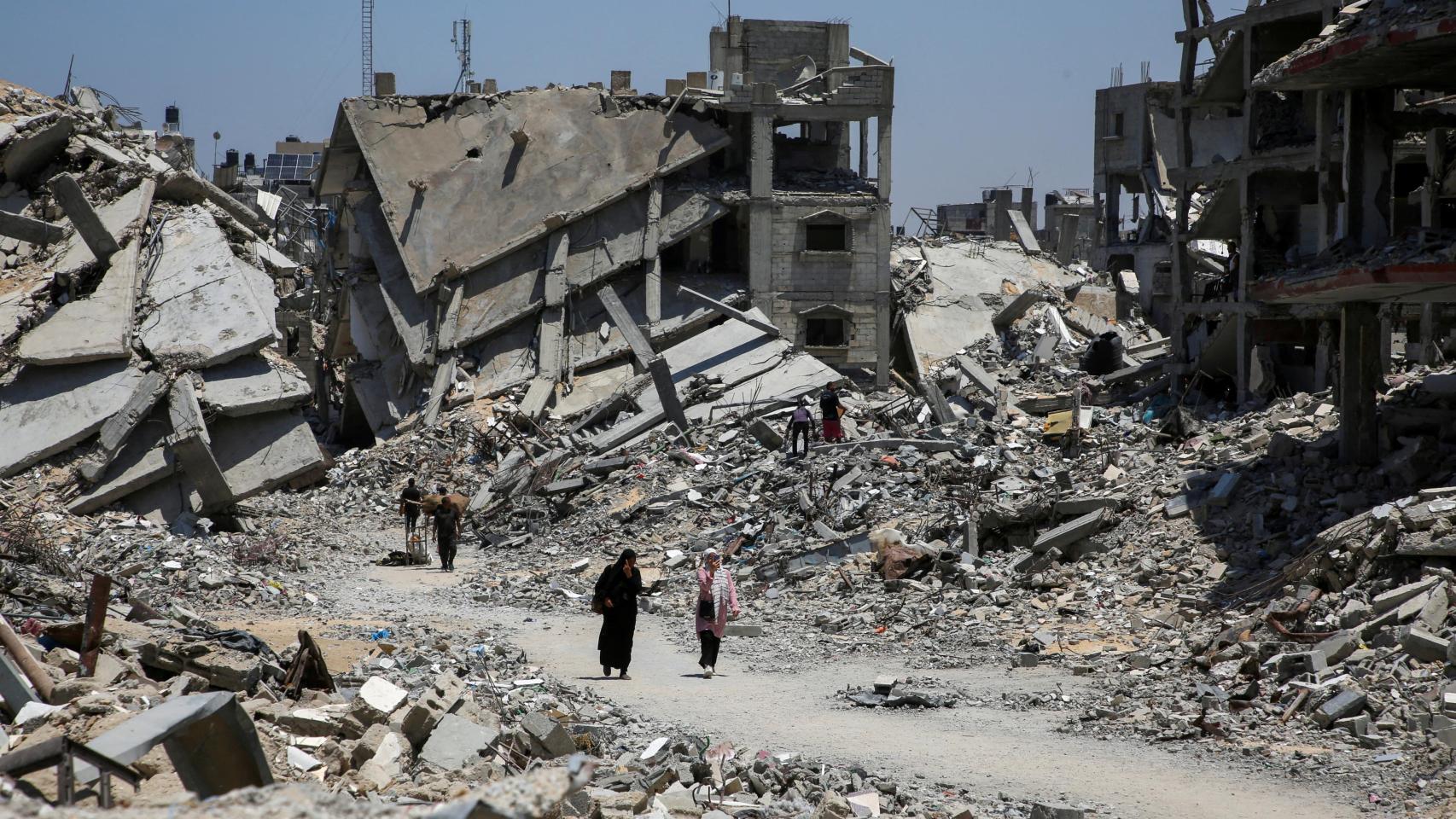 Palestinos caminan junto a los escombros de casas destruidas durante la ofensiva militar israelí, en el sur de la Franja de Gaza.