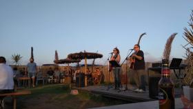 Un grupo de música en  directo cantando en un chiringuito