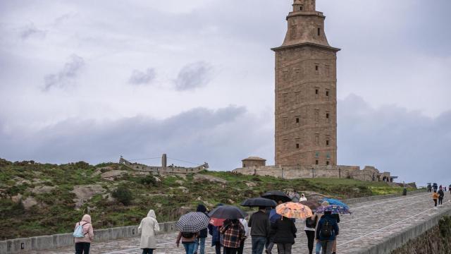 Turistas se protegen de la lluvia ante la Torre de Hércules, en una imagen de archivo.