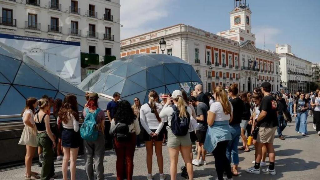 Un grupo de turistas escucha las explicaciones de su guía en la Puerta del Sol.