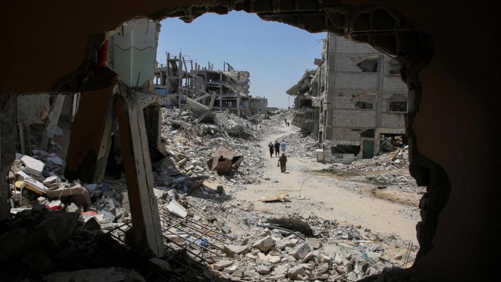 Palestinos pasan junto a los escombros de las casas destruidas por el Ejército de Israel en Jan Yunis, en el sur de Gaza.