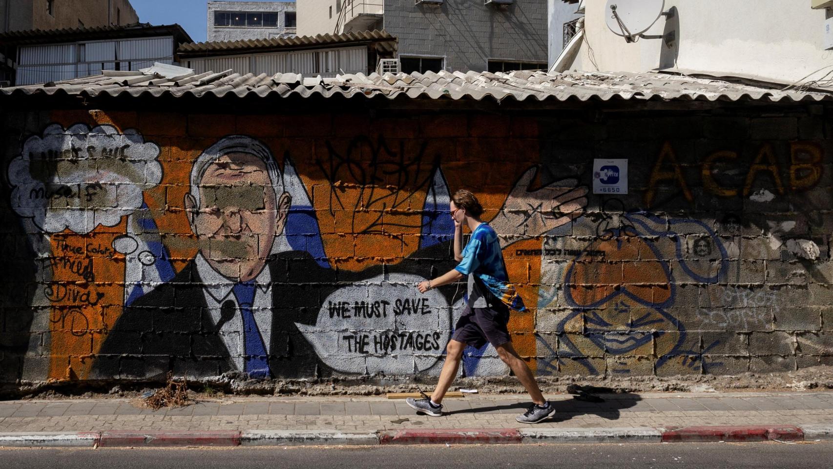 Un hombre pasa junto a un graffiti en contra del primer ministro israelí Benjamin Netanyahu y en apoyo de los rehenes secuestrados durante el mortal ataque del 7 de octubre, en Tel Aviv.