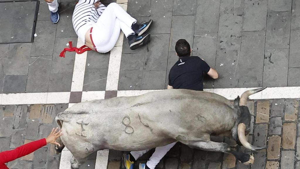 Un toro pasa por encima de un corredor en San Fermín.