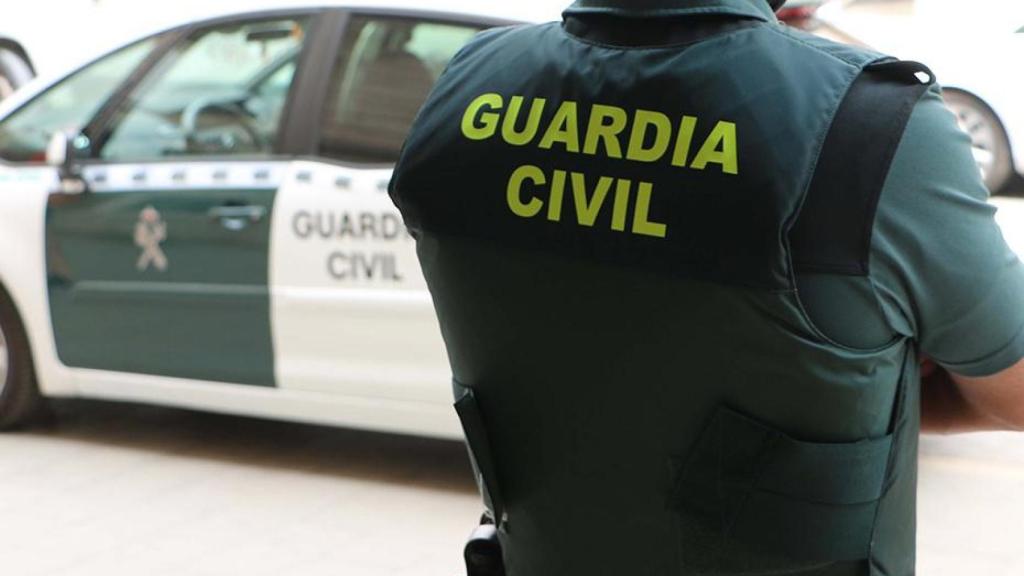 Un agente de la Guardia Civil, de espaldas, junto a un vehículo oficial