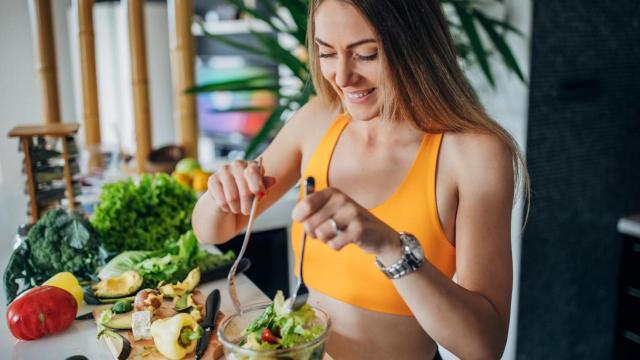 Mujer con ropa de deporte preparándose una ensalada.