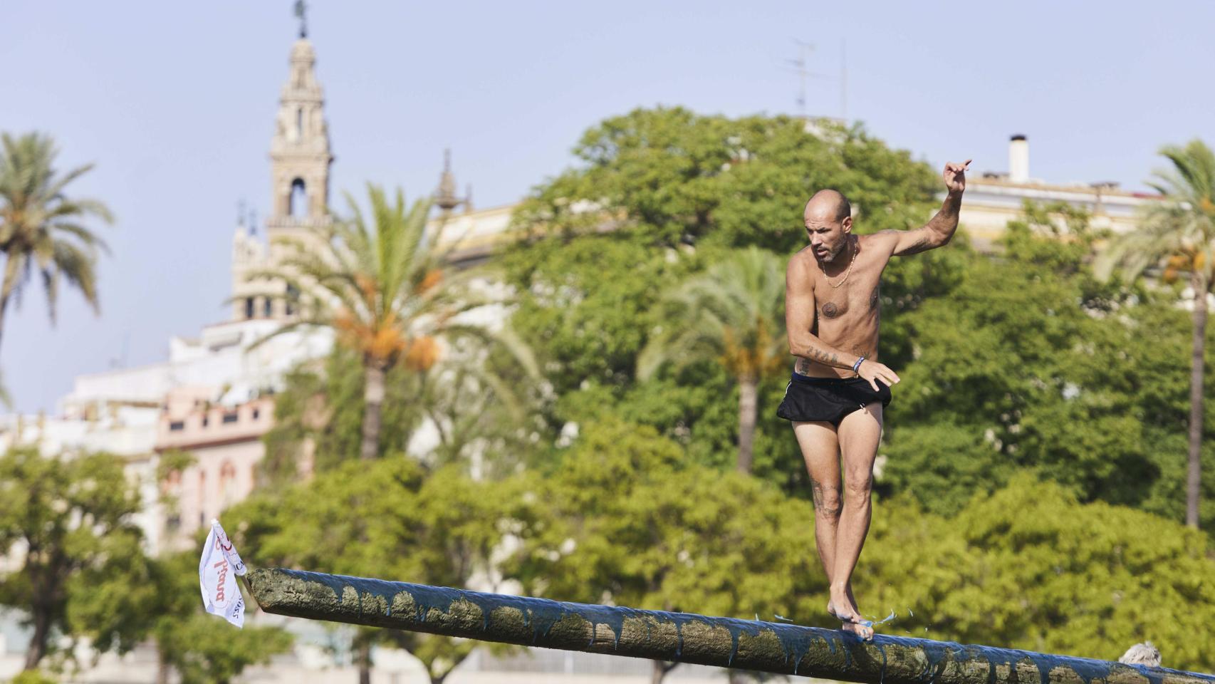 Un joven, en el juego de la cucaña de la Velá de Triana.