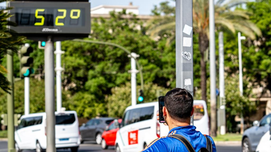 Un turista fotografía un termómetro que marca 52 grados en Sevilla.