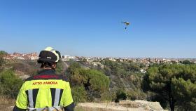 Un efectivo de los Bomberos de Zamora desplegado en la zona del incendio, y en el cielo, el helicóptero de la Junta