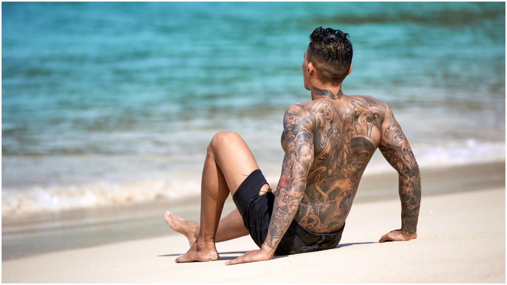 Un hombre con tatuajes en la playa
