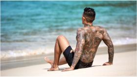Un hombre con tatuajes en la playa