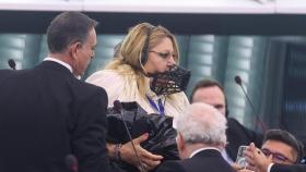 Diana Sosoaca, miembro del Parlamento Europeo y política rumana de extrema derecha, con un bozal en la cara mientras la escoltan fuera del Parlamento Europeo en Estrasburgo, Francia.