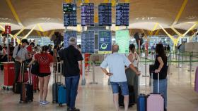 Varias personas con maletas observan el panel de salidas de vuelos en la terminal T4 del Aeropuerto Adolfo Suárez Madrid-Barajas