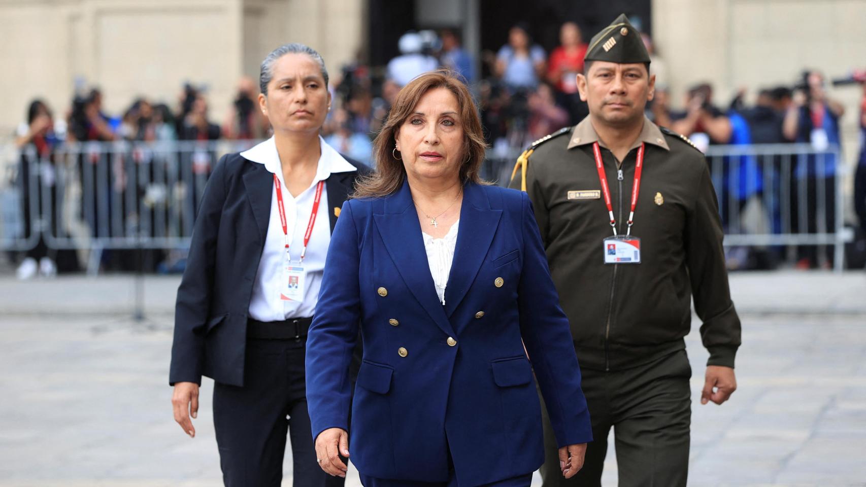 La presidenta de Perú, Dina Boluarte, camina acompañada de dos funcionarios en las afueras del palacio de gobierno.