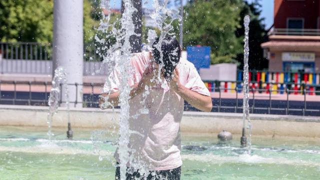 Una persona se refresca en una fuente.