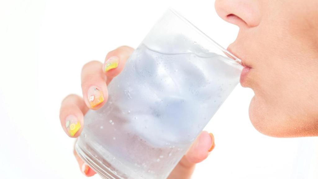 Mujer bebiendo agua con hielo.