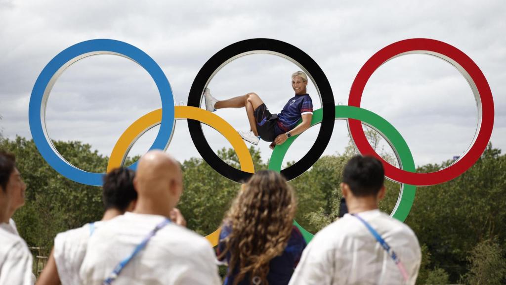 Atletas en la villa olímpica de París fotografiandose junto a los aros olímpicos